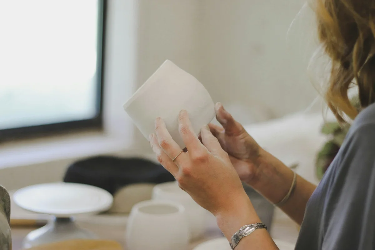 Ceramic artist inspecting the shape of a handmade clay vessel.