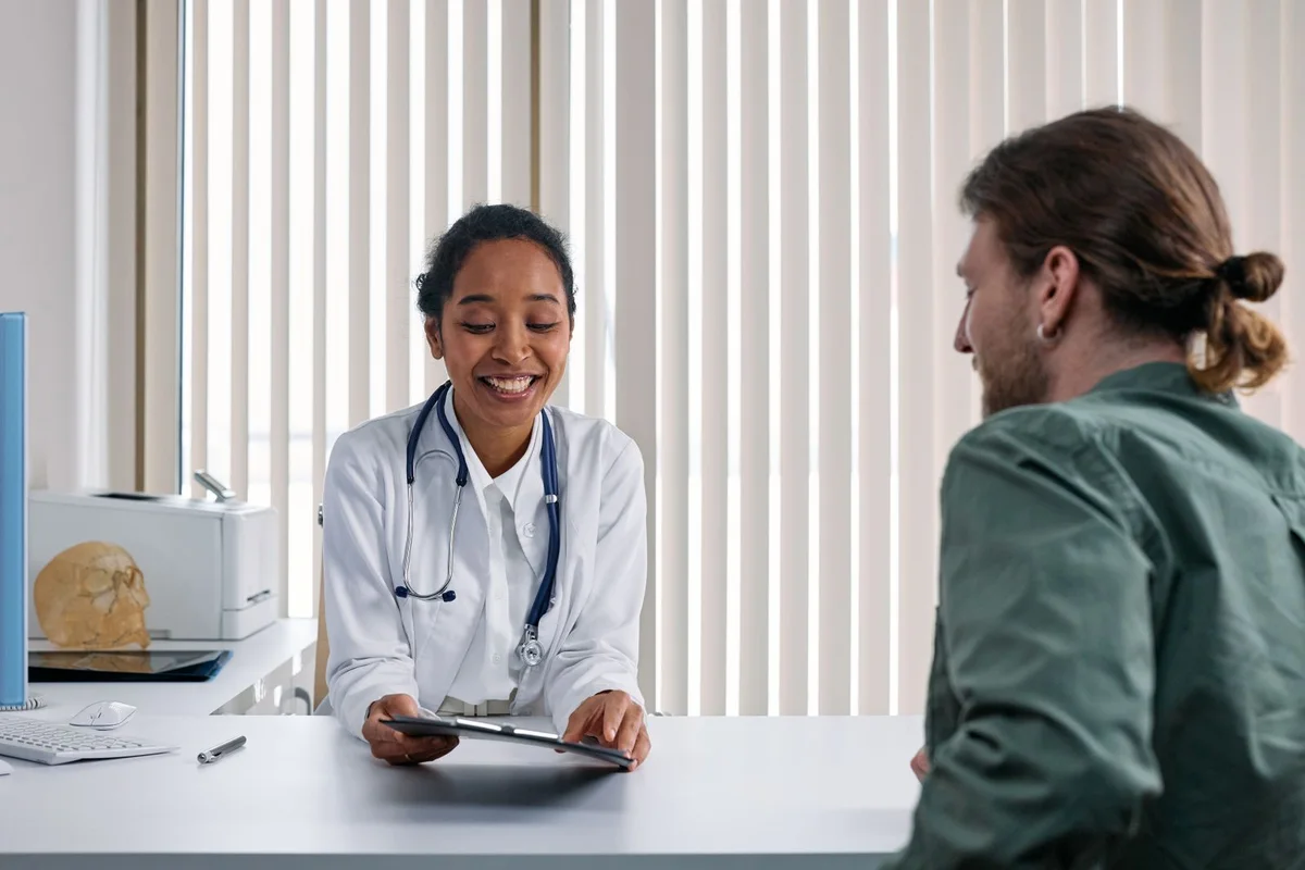 Doctor discussing a clipboard with a patient in a bright consultation room.